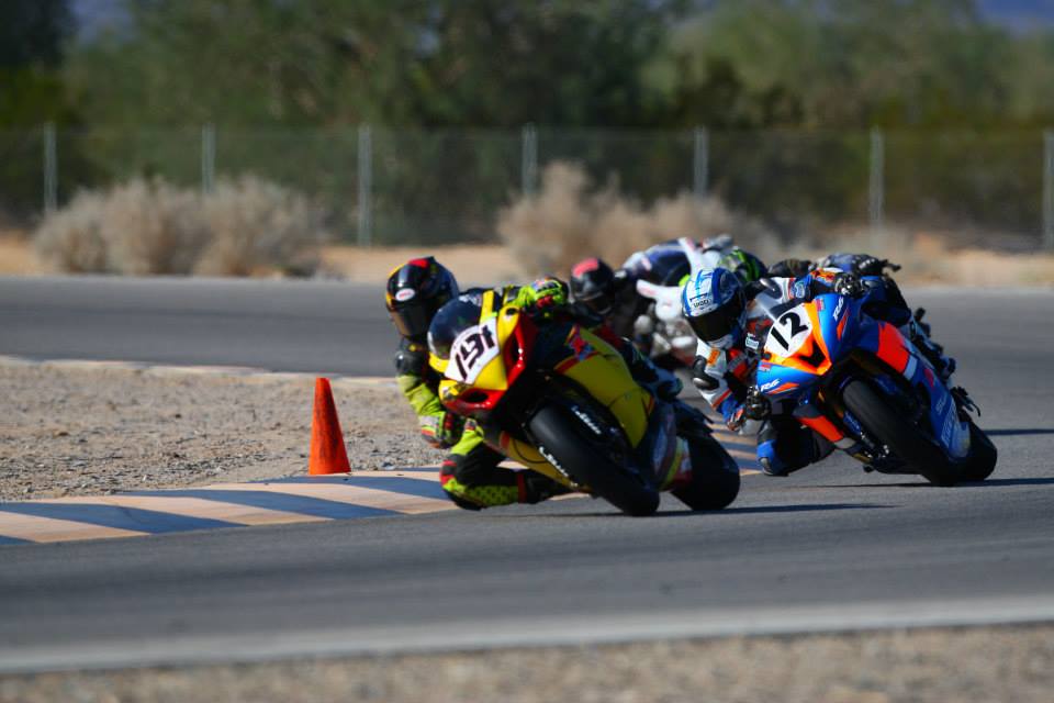 Brian Short number 12 racing in a pack of riders through a corner at Chuckwalla Valley Raceway